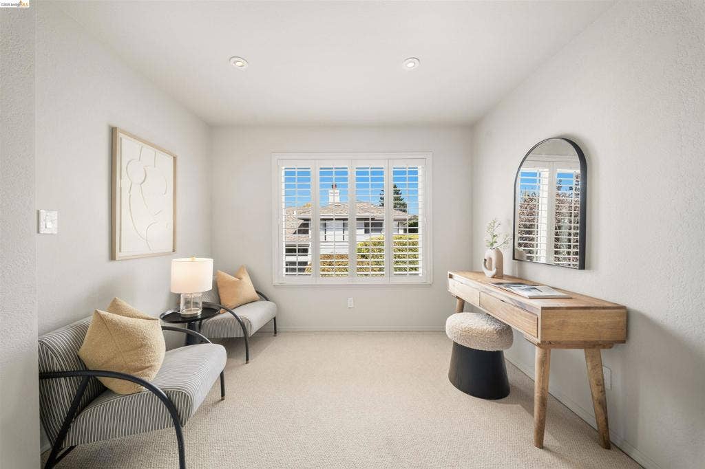 Recessed ceiling lighting, white plantation shutters, neutral carpeting, and a window with exterior views