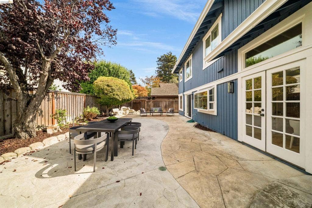 Extensive patio featuring a stamped concrete surface, French doors, and board and batten siding