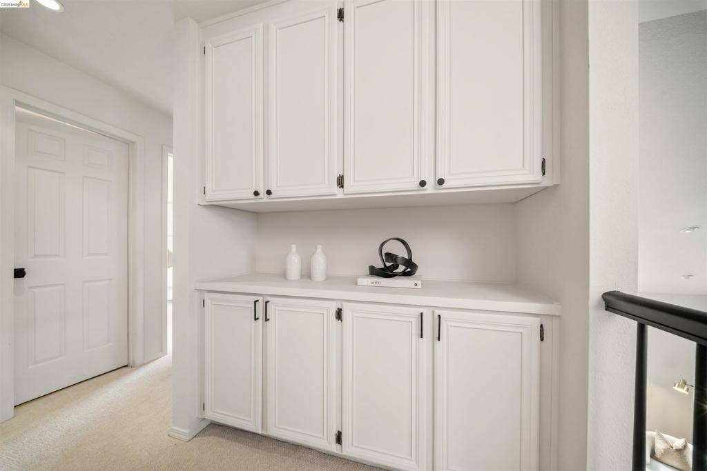 Built-in white cabinetry with beadboard paneling, matte black hardware, and a light-toned countertop