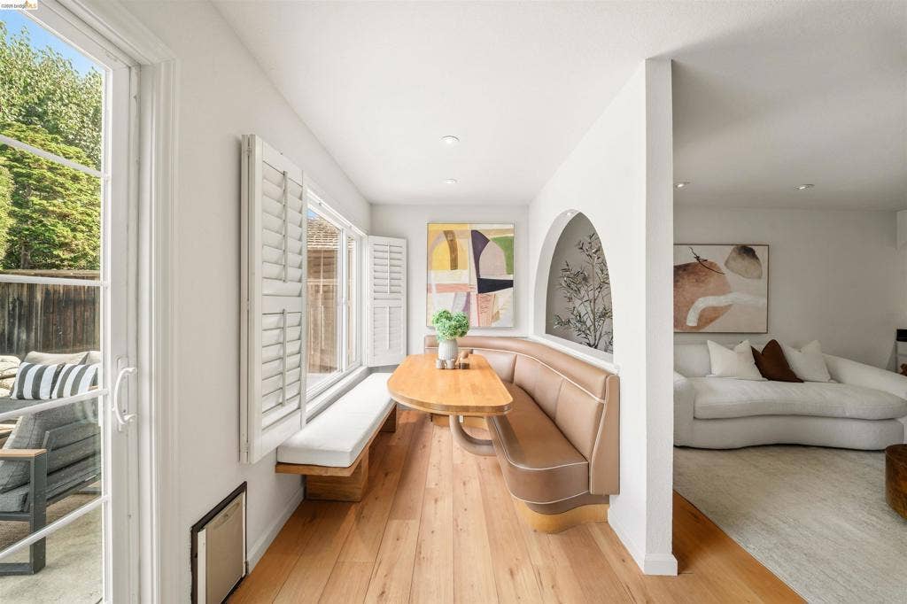 Built-in dining banquette, wood-finish flooring, sliding glass door, multiple windows with plantation shutters, recessed lighting