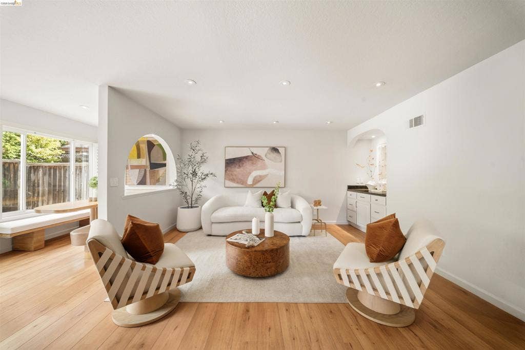 Hardwood flooring, recessed lighting, arched wall opening, built-in window seating, built-in cabinetry with dark countertop