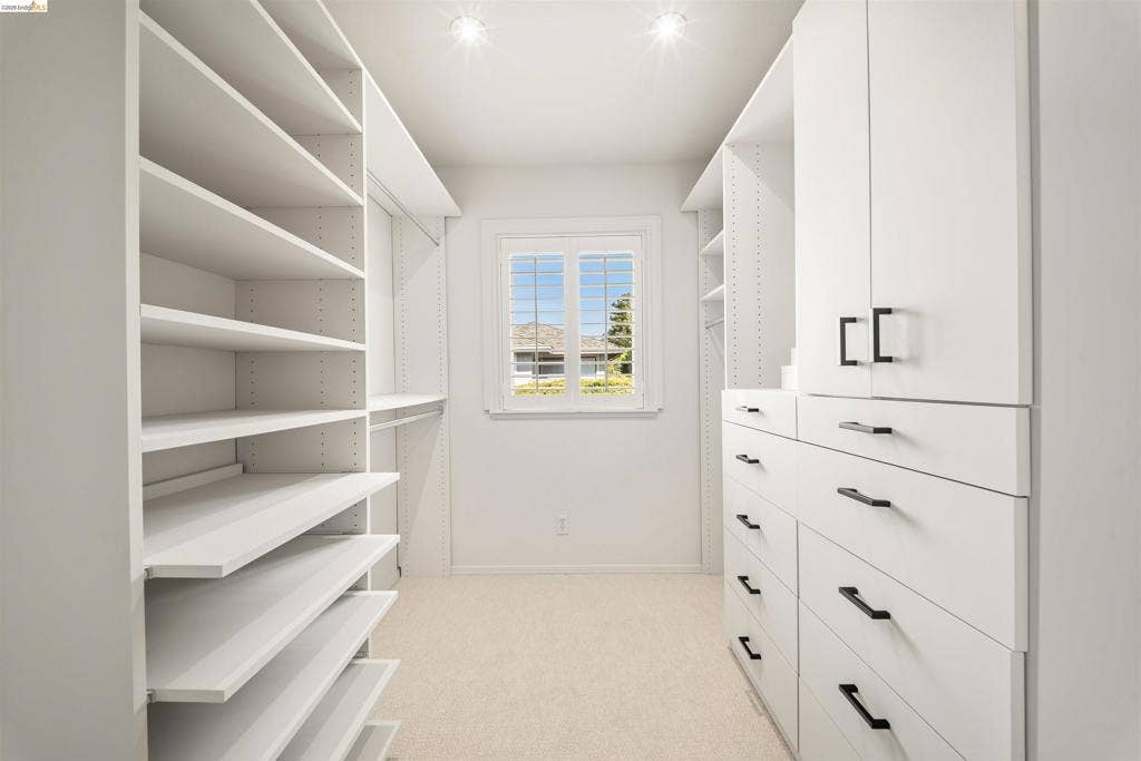 Custom built-in closet system featuring extensive shelving, integrated drawers with dark hardware, and cabinet storage