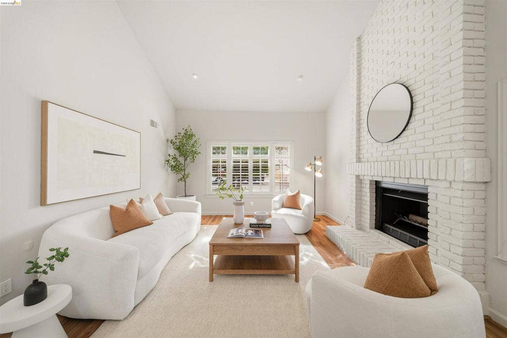 Living area featuring a painted brick fireplace, vaulted ceiling, wood-finish flooring, recessed lighting, and a window with plantation shutters
