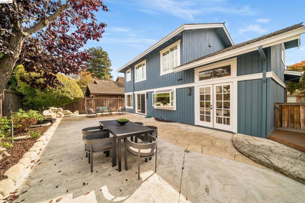 Expansive stamped concrete patio with garden beds, a mature tree, and a multi-level deck