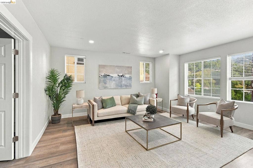 Recessed lighting, wood-finish flooring, multiple windows, white interior doors, and crisp white trim