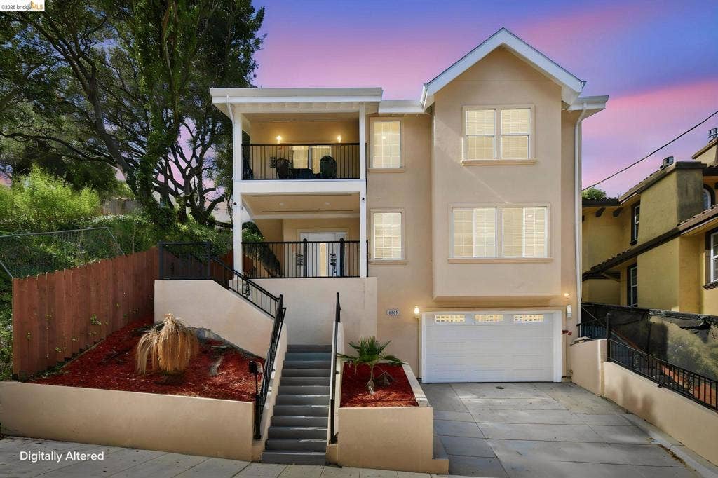 Multi-level property with two balconies, attached garage, and exterior staircase with wrought iron railings