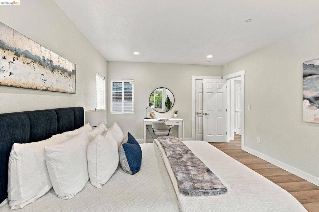 Recessed lighting, wood-finish flooring, white paneled doors, and a window with blinds