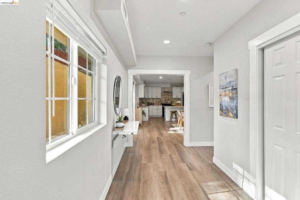 Light wood-finish flooring, recessed lighting, white trim, and a white paneled door