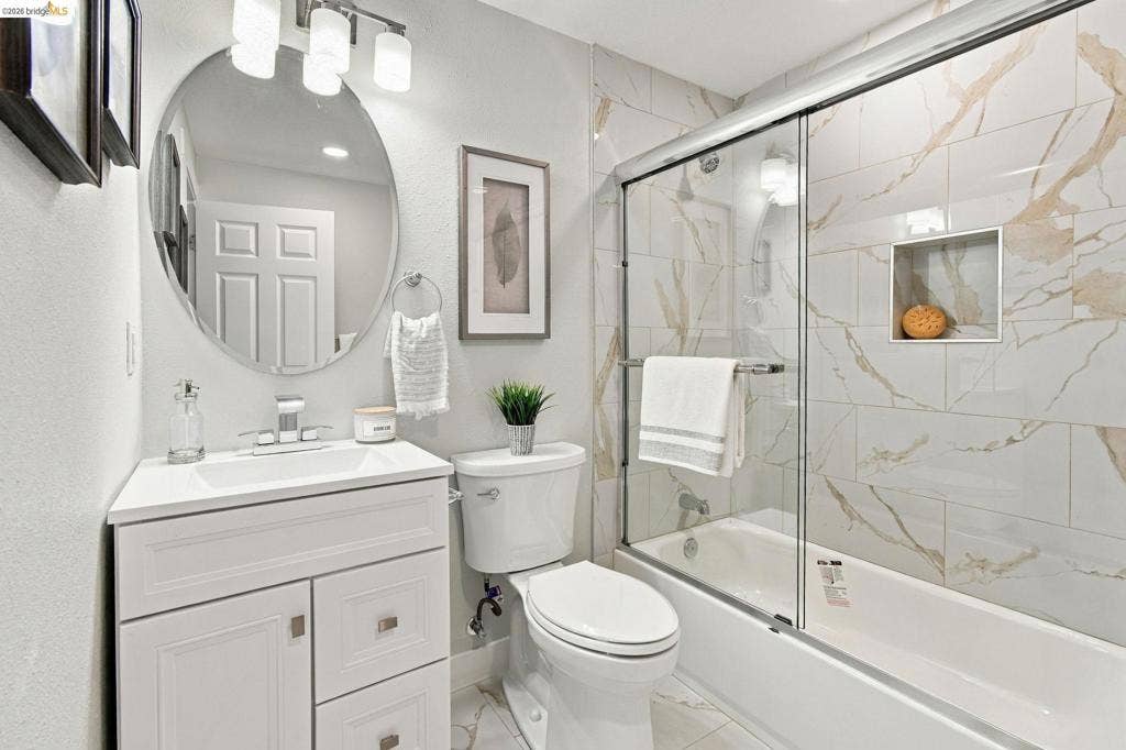 White vanity with integrated sink, chrome faucet, and overhead lighting
