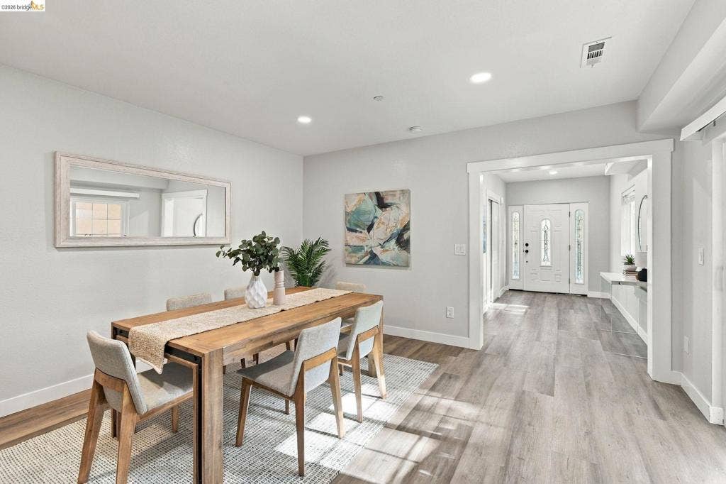 Wood-finish flooring throughout, recessed lighting, and a white paneled entry door with decorative glass inserts