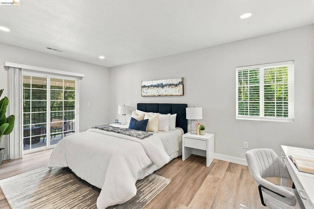 Recessed lighting, wood-finish flooring, sliding glass door with balcony access, and a window with blinds