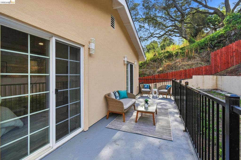 Exterior patio with a stucco finish, sliding glass doors, and a black metal railing