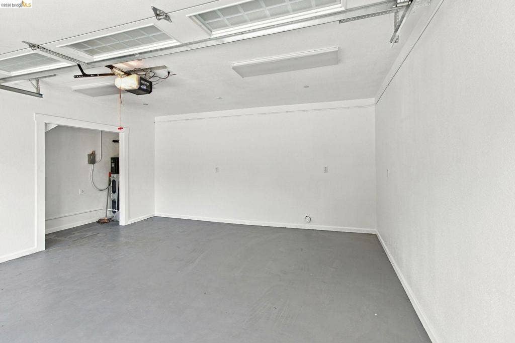 Concrete flooring, white painted walls, and overhead lighting