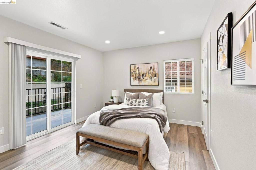 Sliding glass door with exterior railing, wood-finish flooring, recessed lighting, and a single window