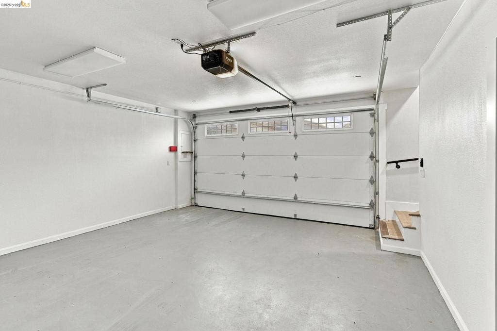 Attached garage with a sectional overhead door, integrated windows, concrete flooring, and an automatic garage door opener