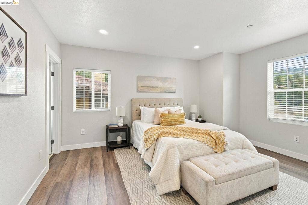 Wood-finish flooring, recessed lighting, and multiple windows with blinds