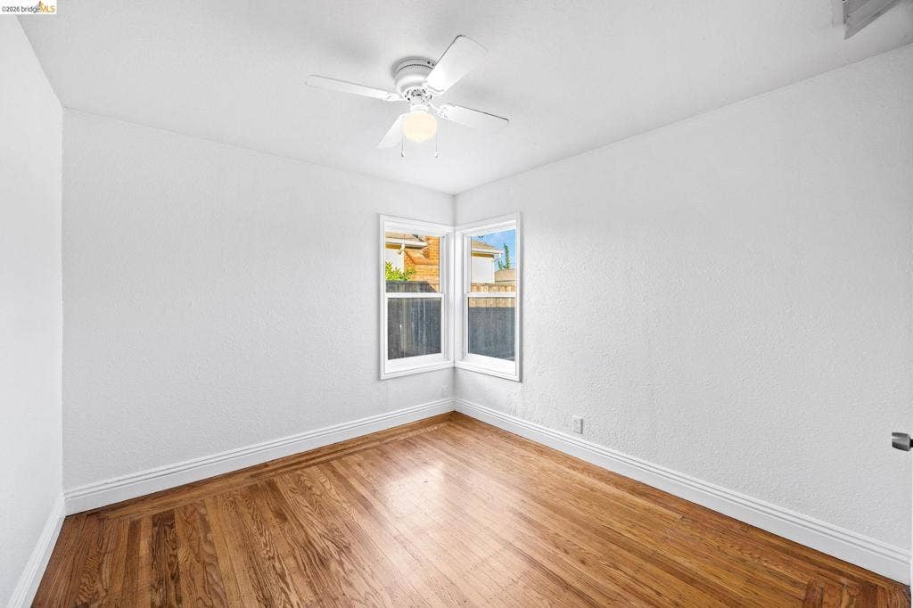 2240 Lessley Ave, Castro Valley, CA 94546 Hardwood flooring and white baseboards complement the corner window with white trim, and a ceiling fan with light fixture