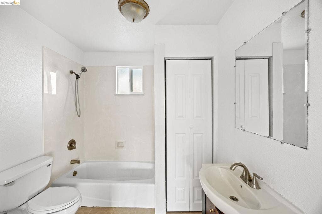 2240 Lessley Ave, Castro Valley, CA 94546 White bathroom featuring a built-in tub with shower, single-pane window, and a wall-mounted mirror