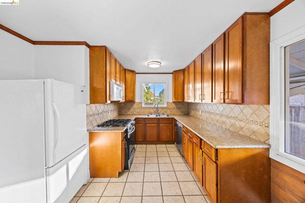 2240 Lessley Ave, Castro Valley, CA 94546 U-shaped kitchen featuring wood cabinetry, light-toned countertops, a tile backsplash, and tile flooring