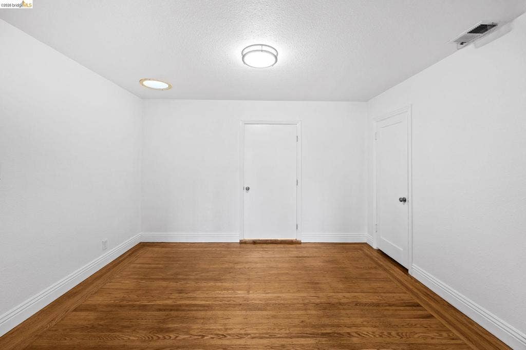 2240 Lessley Ave, Castro Valley, CA 94546 Wood-finish flooring, white walls, and a contemporary ceiling light fixture