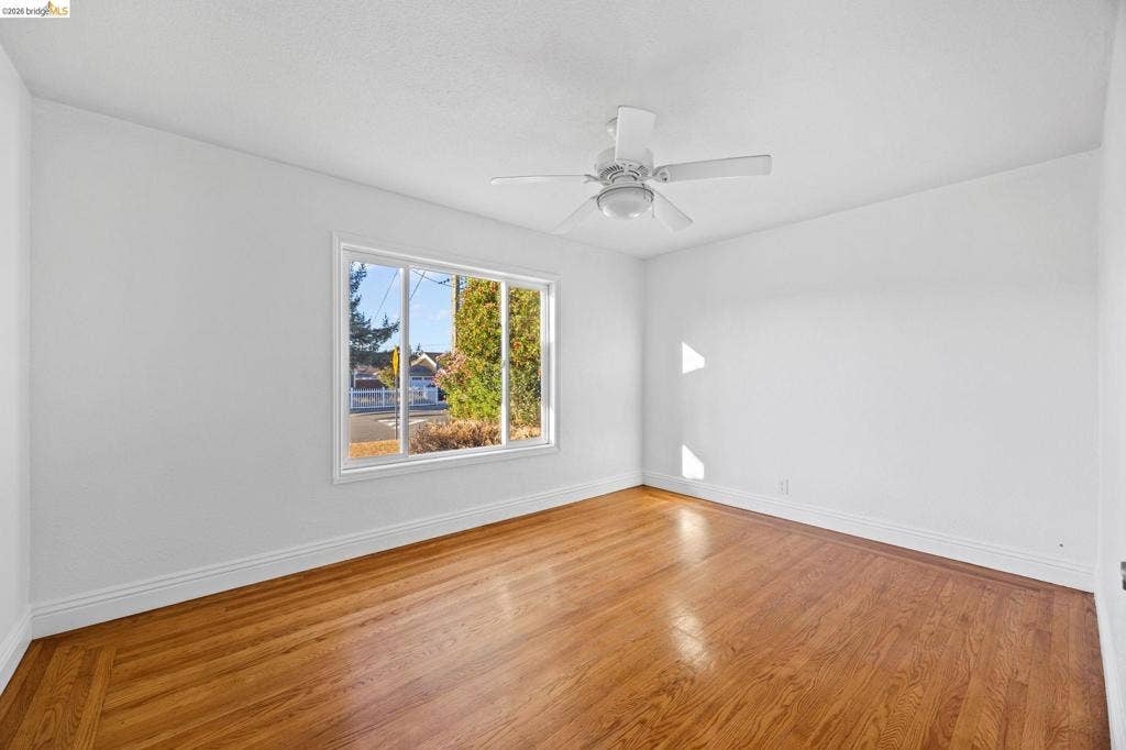 2240 Lessley Ave, Castro Valley, CA 94546 Hardwood flooring, white walls, white trim, white ceiling fan, and a large window