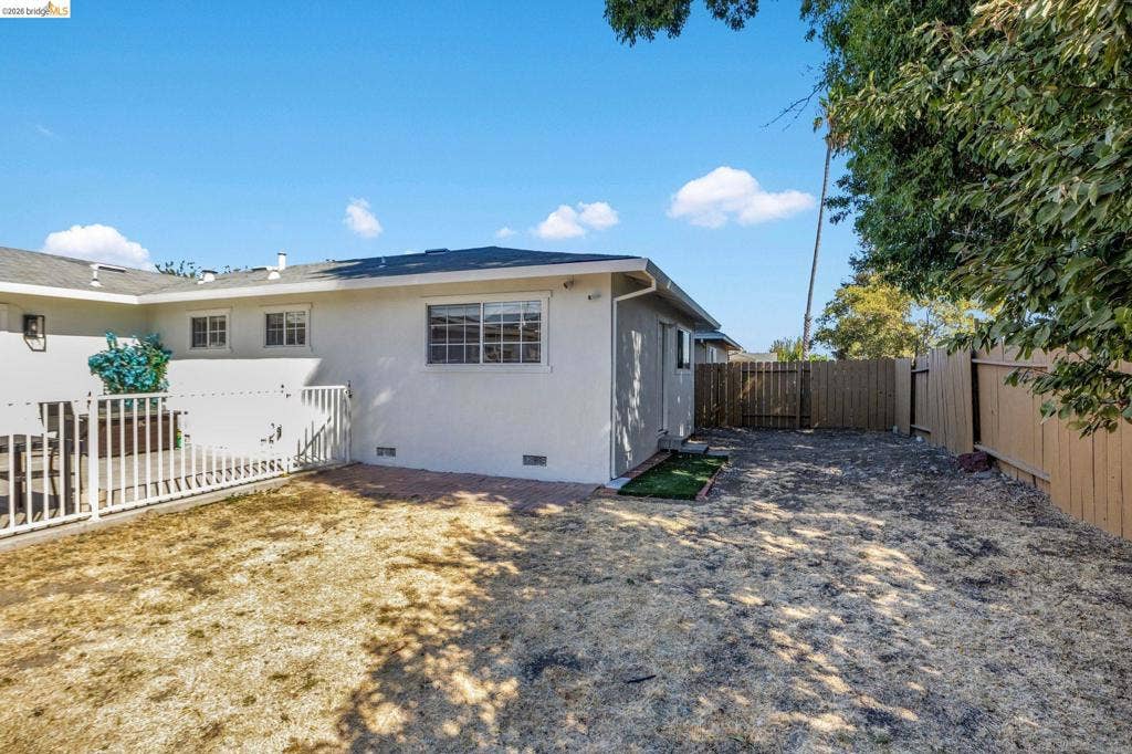 1509 Poppy Way, Antioch, CA 94509 Expansive backyard featuring a stucco exterior, multiple windows, a white picket fence, and wooden fencing