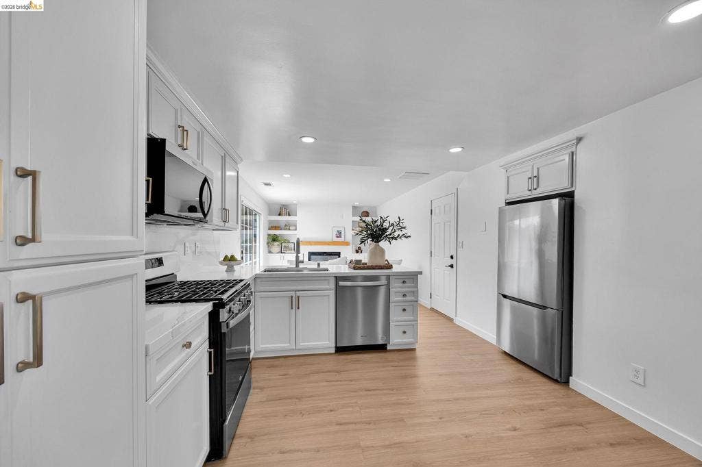 1509 Poppy Way, Antioch, CA 94509 White shaker cabinetry with brushed gold hardware, stainless steel appliances, wood-finish flooring, recessed lighting, and a white tile backsplash
