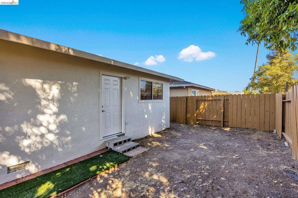1509 Poppy Way, Antioch, CA 94509 Stucco exterior with a paneled door, a single window, and a wood fence enclosing the yard