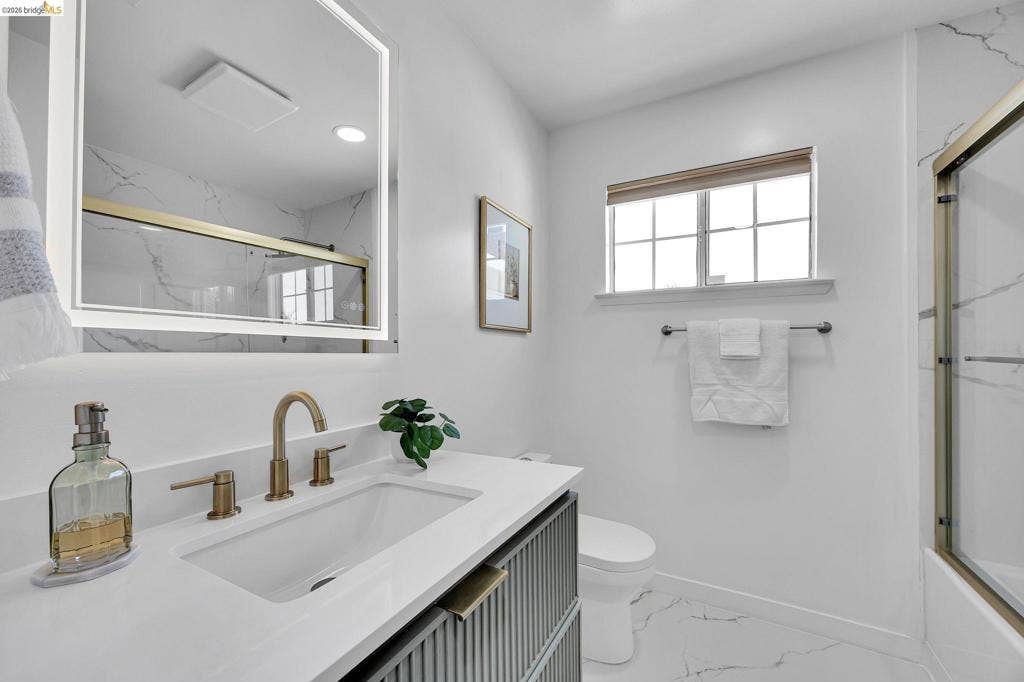 1509 Poppy Way, Antioch, CA 94509 White quartz-finish countertop, undermount sink with brass-finish fixtures, backlit mirror, vanity with textured paneling, and a window with privacy blind