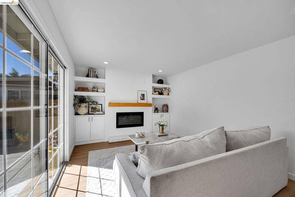 1509 Poppy Way, Antioch, CA 94509 Sliding glass door with grid pattern, recessed lighting, wood-finish flooring, built-in shelving, and a wall-mounted fireplace