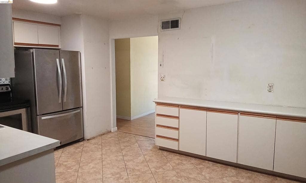 145 Viking Way, Pittsburg, CA 94565 Tile flooring, white cabinetry with wood-finish trim, white countertops, and a stainless steel refrigerator