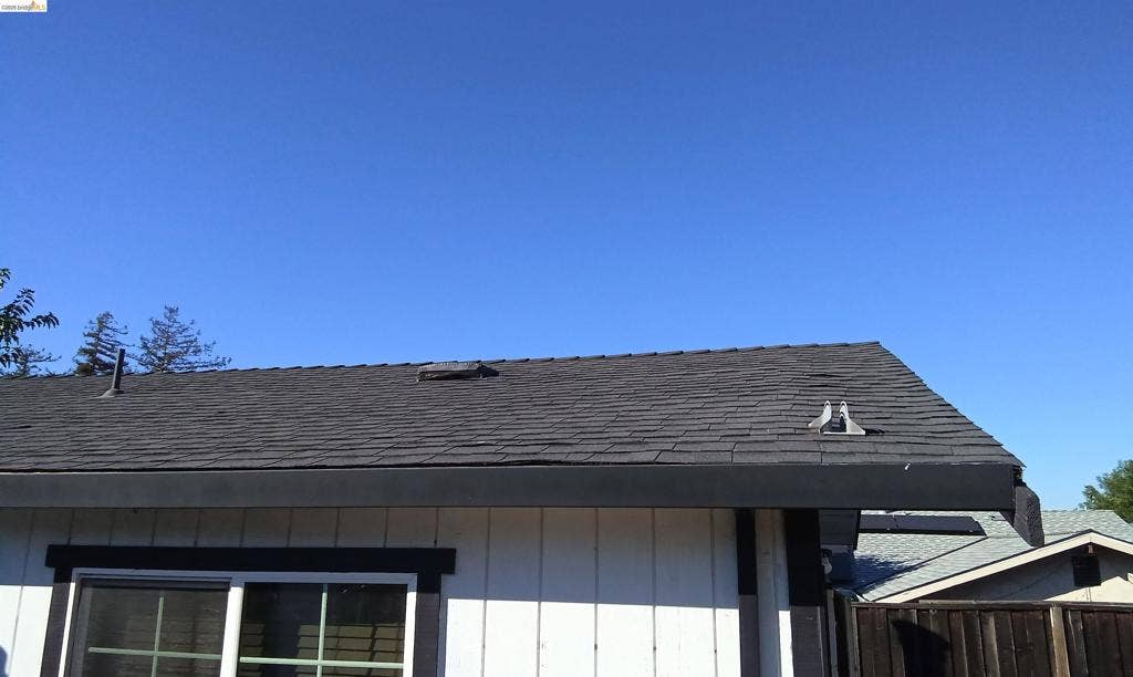 145 Viking Way, Pittsburg, CA 94565 Dark shingle roof, white vertical siding, dark trim, and a sliding window
