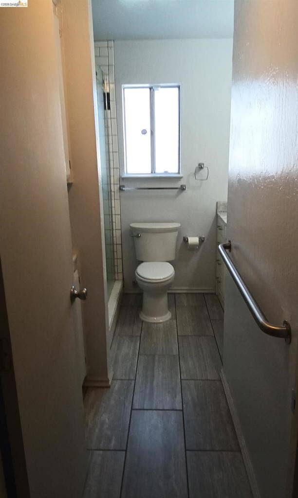 145 Viking Way, Pittsburg, CA 94565 Tile flooring with a rectangular window, a built-in shower with a glass enclosure, and a wall-mounted grab bar