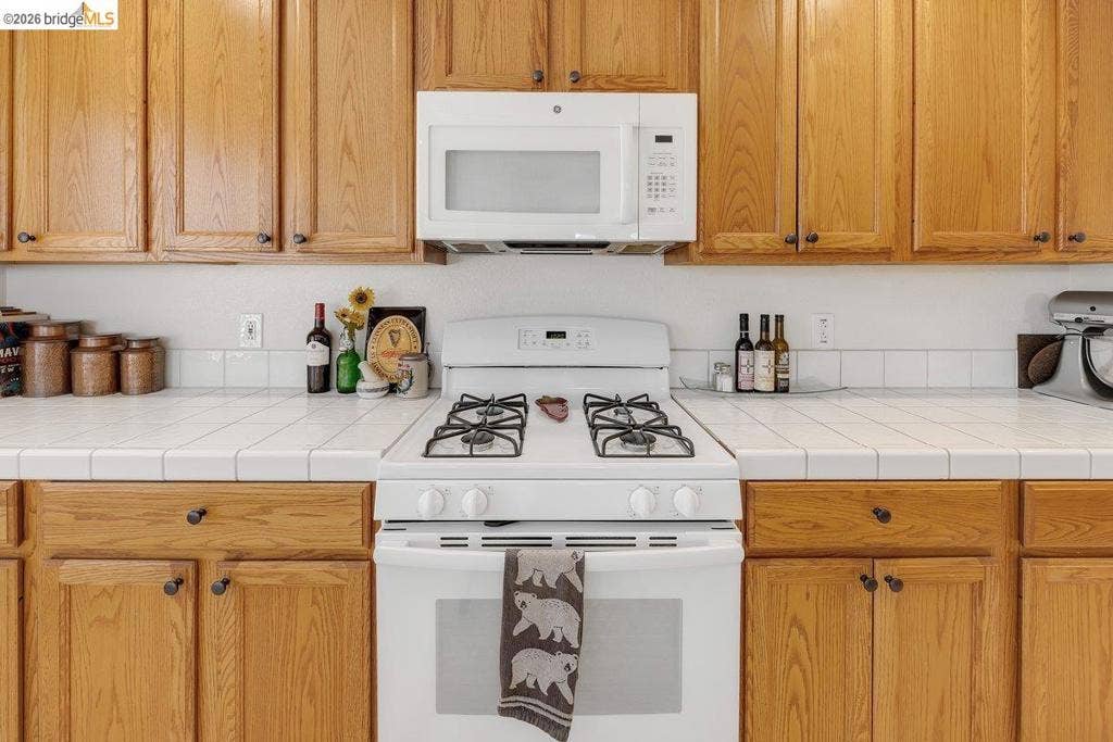 981 Country Ln, Angels Camp, CA 95222 Wood-finish cabinetry paired with white tiled countertops and a matching tiled backsplash