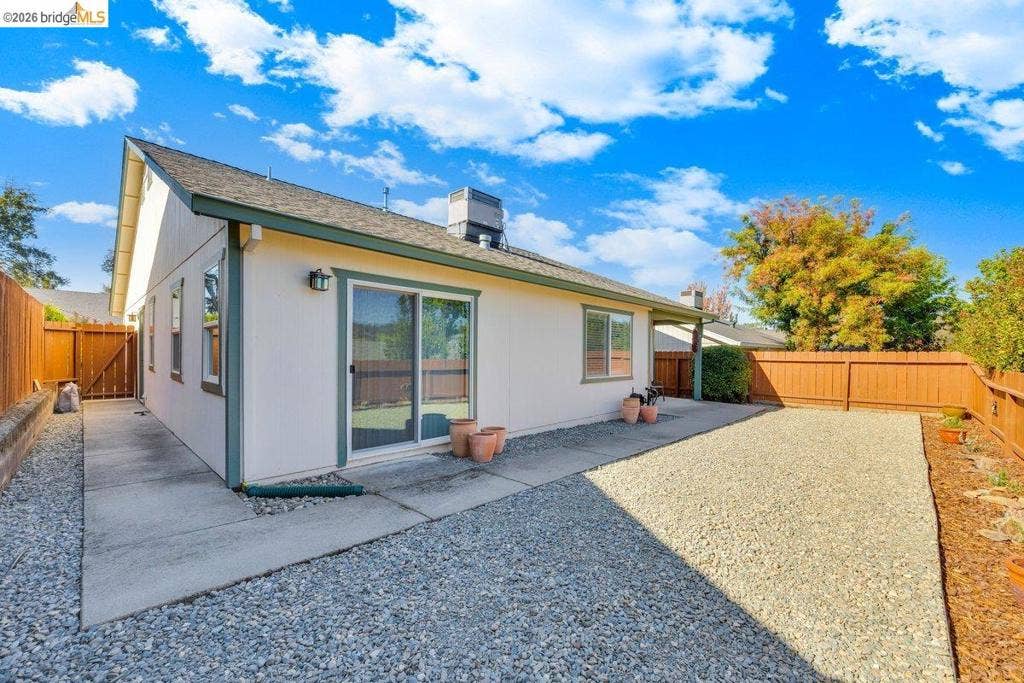 981 Country Ln, Angels Camp, CA 95222 Exterior featuring stucco siding, a composition shingle roof, sliding glass door, and a gravel-covered yard