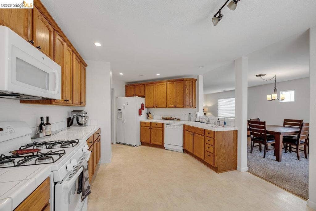 981 Country Ln, Angels Camp, CA 95222 Kitchen featuring wood cabinetry, white tile countertops, recessed lighting, and white appliances including an oven with gas cooktop and an overhead microwave