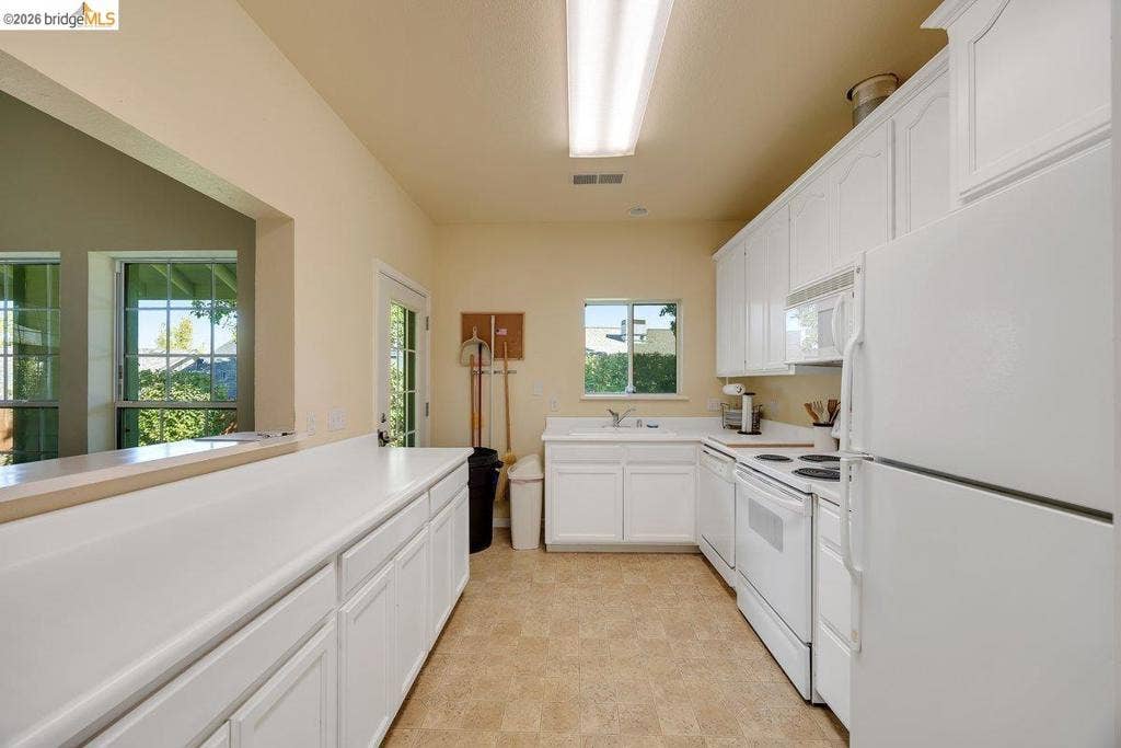981 Country Ln, Angels Camp, CA 95222 Kitchen featuring white cabinetry, white appliances, a window above the sink, and a door with a glass pane