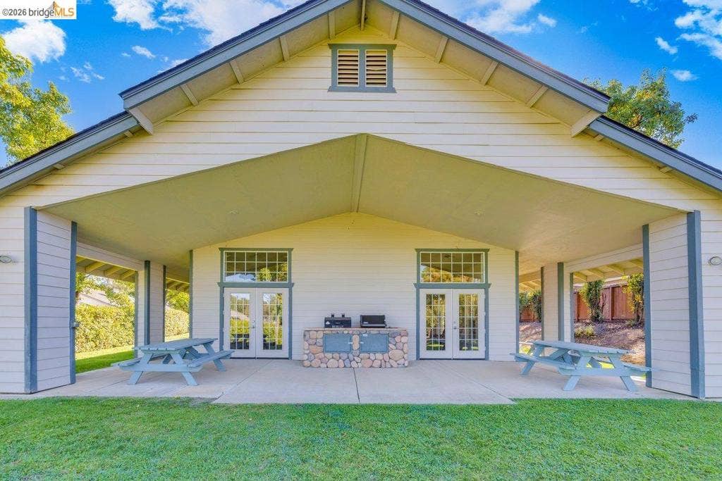 981 Country Ln, Angels Camp, CA 95222 Covered patio with a built-in stone outdoor kitchen, dual French doors, and an expansive lawn