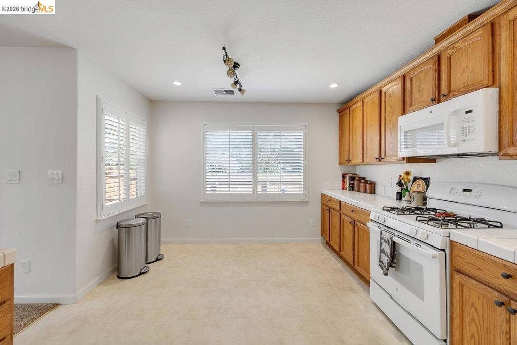 981 Country Ln, Angels Camp, CA 95222 Kitchen featuring wood cabinetry, white countertops, gas range, built-in microwave, and plantation shutters