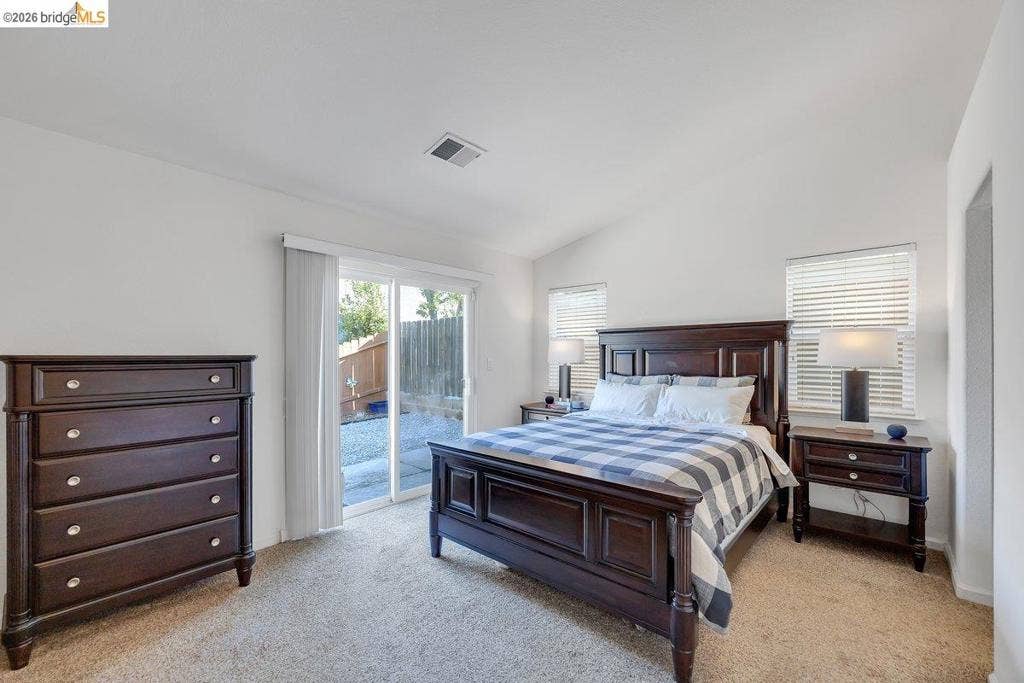 981 Country Ln, Angels Camp, CA 95222 Vaulted ceiling, carpeted flooring, sliding glass door, two windows with blinds, and white painted walls