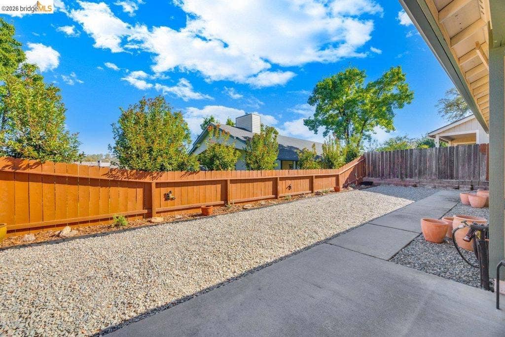 981 Country Ln, Angels Camp, CA 95222 Expansive backyard featuring a wood fence, gravel landscaping, and a concrete patio