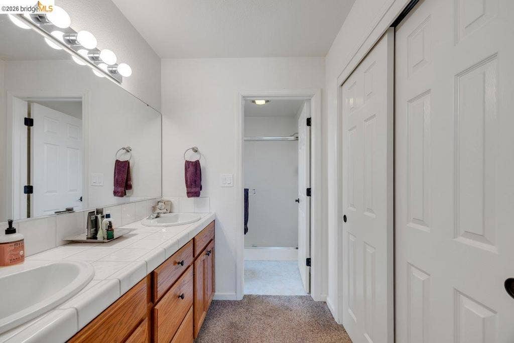 981 Country Ln, Angels Camp, CA 95222 Double vanity with integrated sinks, wood cabinetry, and tiled countertop