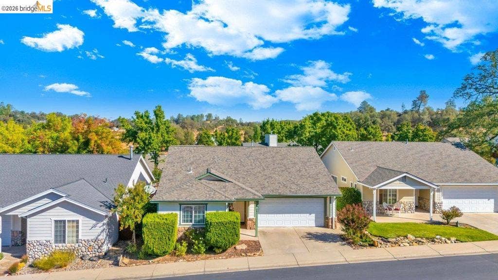 981 Country Ln, Angels Camp, CA 95222 Single-story residence featuring a shingle roof, attached garage, and a concrete driveway