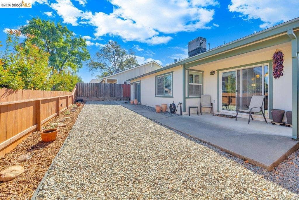 981 Country Ln, Angels Camp, CA 95222 Private backyard featuring a concrete patio, sliding glass door, and a wood privacy fence