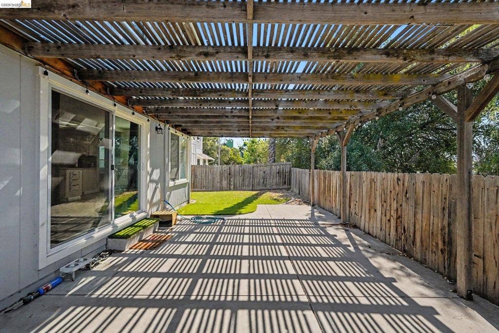 304 Greystone Dr, Antioch, CA 94509 Concrete patio featuring a slatted wood pergola, sliding glass door, and wooden perimeter fencing