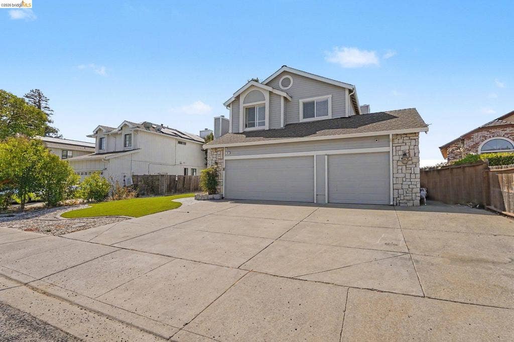 304 Greystone Dr, Antioch, CA 94509 Exterior featuring light-toned horizontal siding, stone veneer accents, a concrete driveway, two-car garage, and a manicured synthetic turf lawn