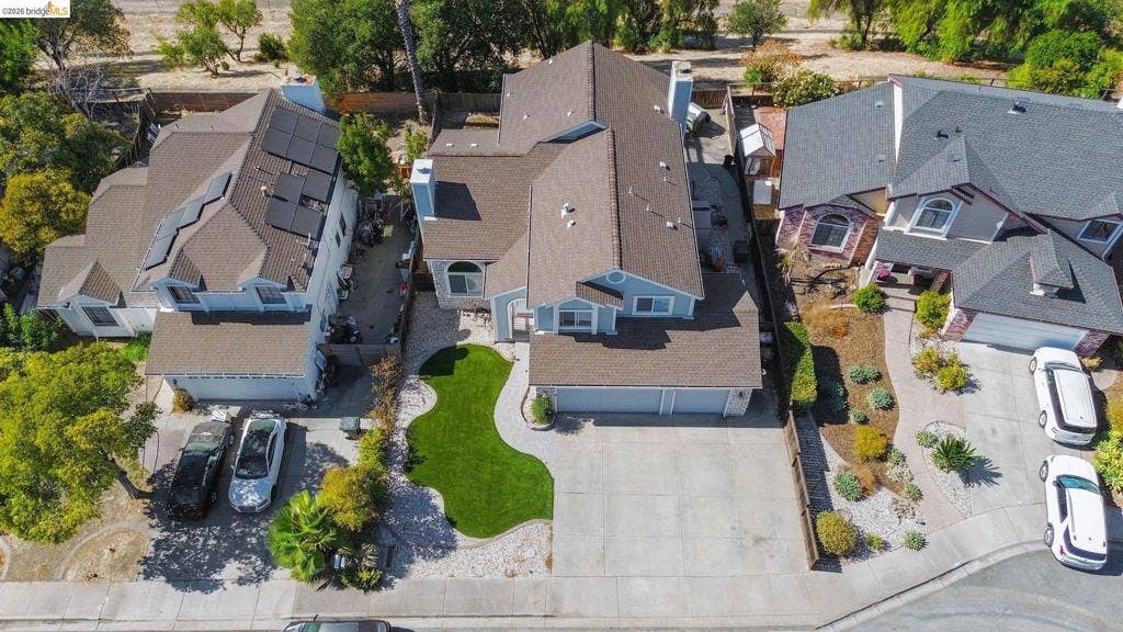 304 Greystone Dr, Antioch, CA 94509 Aerial perspective of a multi-level residence featuring a multi-car garage, pitched roofline, integrated chimney, and a landscaped front yard with a manicured lawn