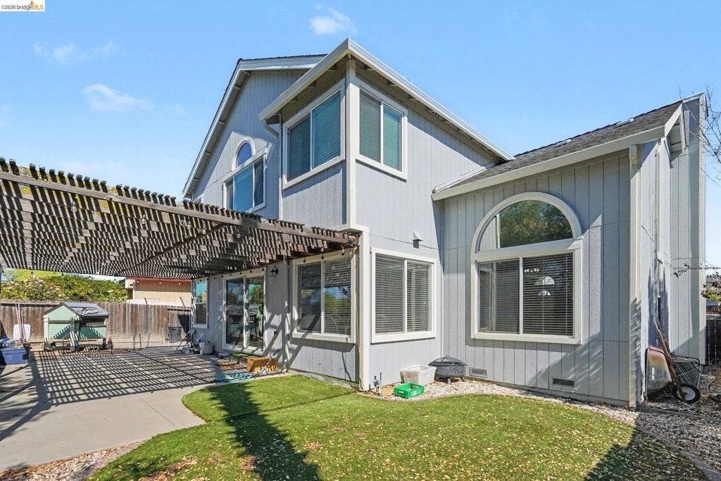 304 Greystone Dr, Antioch, CA 94509 Two-story exterior featuring vertical siding, an attached pergola, arched windows, and a concrete patio