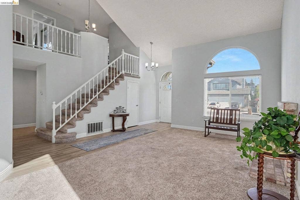 304 Greystone Dr, Antioch, CA 94509 Vaulted ceilings, staircase with white railing, arched window, and wood-finish flooring