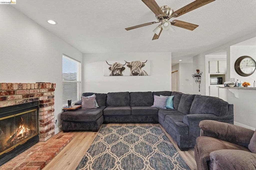 304 Greystone Dr, Antioch, CA 94509 Living area featuring a floor-to-ceiling brick fireplace with a raised hearth, wood-finish flooring, recessed lighting, and a ceiling fan
